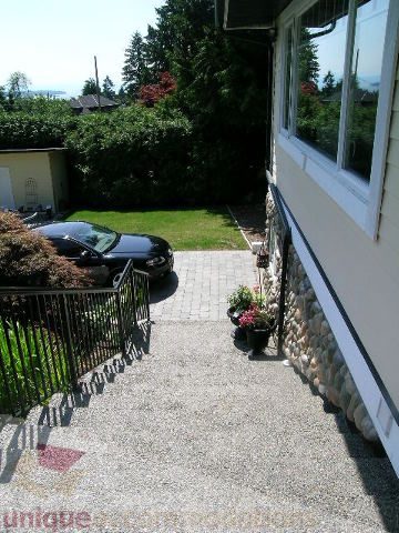 Bright patio with stone walls and lush greenery, perfect for relaxation. - 4104 Sunnycrest drive, North Vancouver