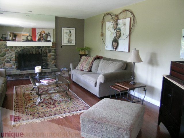 Furnished living room with stone fireplace, patterned rug, and artwork on the walls. - 4104 Sunnycrest drive, North Vancouver