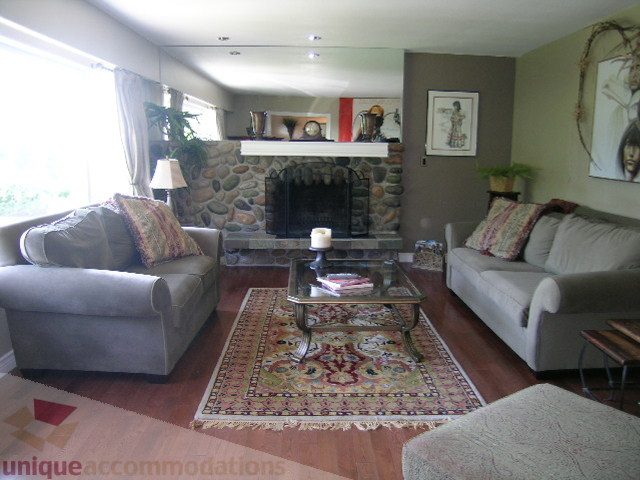 Living room with stone fireplace, hardwood floors, and a large area rug. - 4104 Sunnycrest drive, North Vancouver