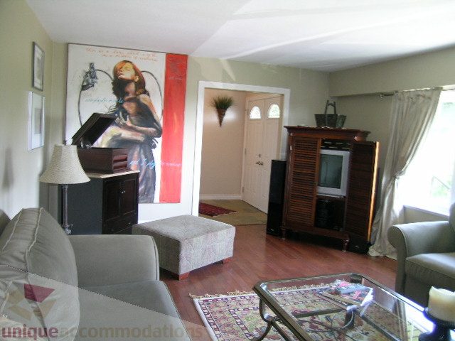 Living room with hardwood floors, large artwork, and a cozy sofa. - 4104 Sunnycrest drive, North Vancouver