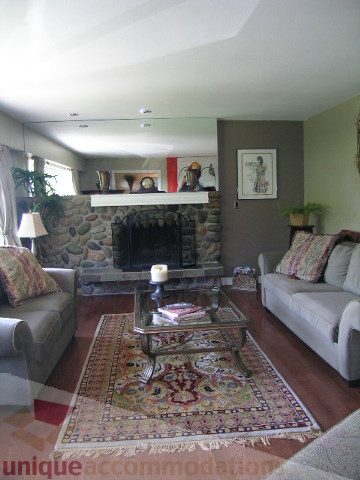 Furnished living room with stone fireplace, patterned rug, and comfortable seating. - 4104 Sunnycrest drive, North Vancouver