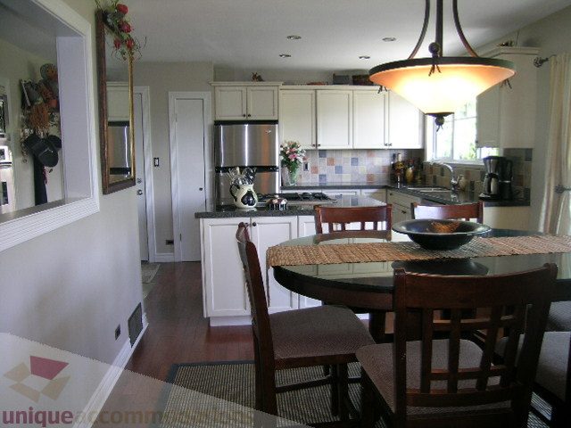 Bright kitchen with white cabinets, stainless steel appliances, and hardwood floors. - 4104 Sunnycrest drive, North Vancouver