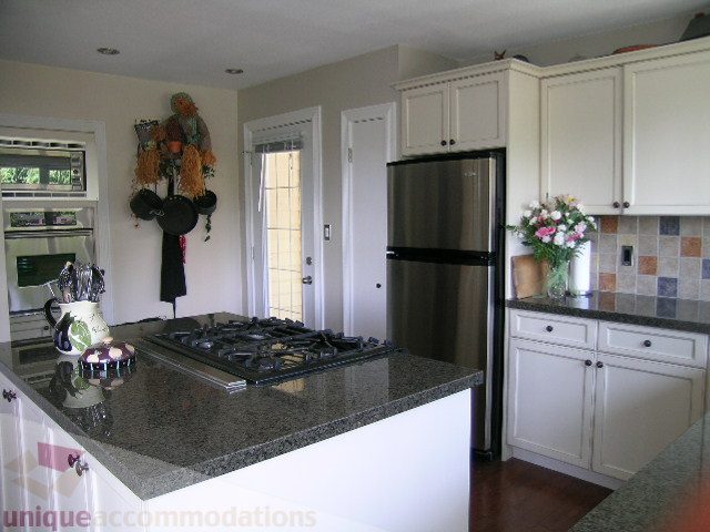 Bright kitchen with granite countertops, stainless steel appliances, and white cabinetry. - 4104 Sunnycrest drive, North Vancouver