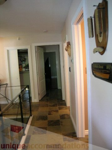 Bright hallway leading to kitchen and living area; tiled floor, wooden door, wall decor. - 4104 Sunnycrest drive, North Vancouver