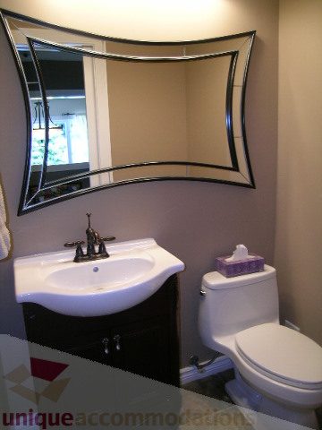 Bathroom with curved mirror, white sink, and toilet. - 4104 Sunnycrest drive, North Vancouver