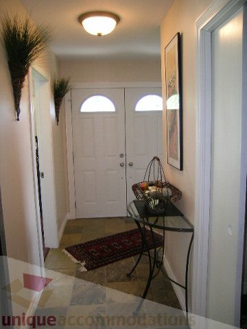 Foyer with double doors, decorative wall art, and a small bench. - 4104 Sunnycrest drive, North Vancouver