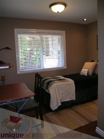 Bright living room with a large window, blinds, and a cozy sofa. - 4104 Sunnycrest drive, North Vancouver