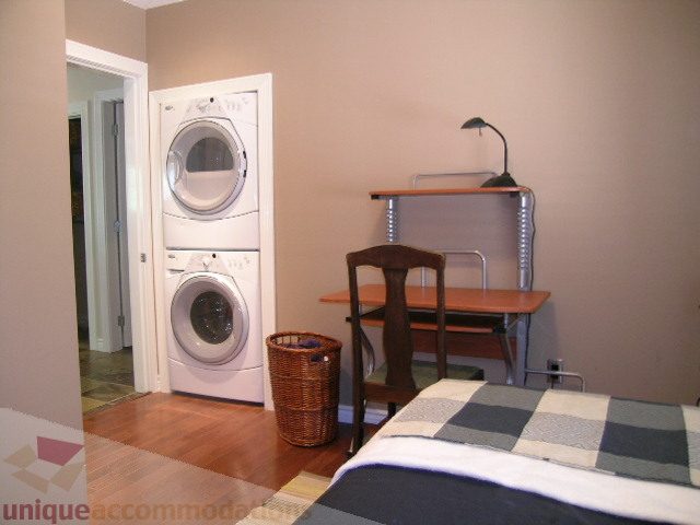 Bright bedroom with wooden floors, desk, and laundry area. - 4104 Sunnycrest drive, North Vancouver