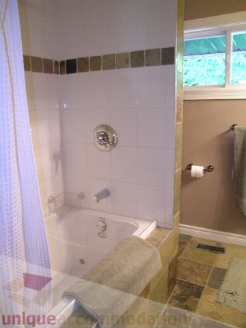 Bathroom with tiled walls, shower curtain, and window view. - 4104 Sunnycrest drive, North Vancouver