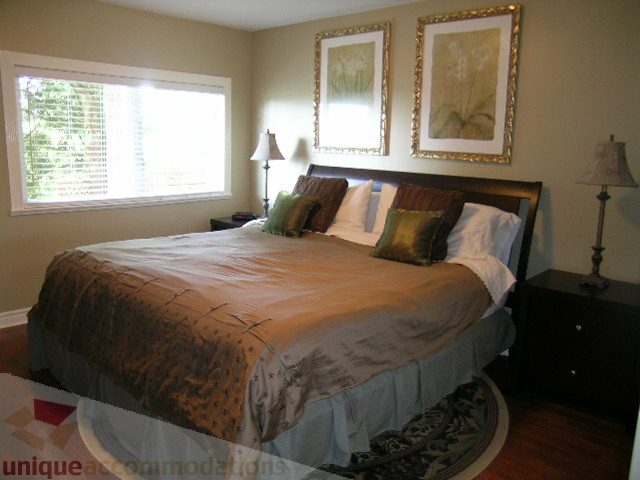 Spacious bedroom with large window, floral bedding, and framed artwork. - 4104 Sunnycrest drive, North Vancouver