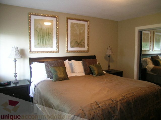 Furnished bedroom with two queen beds, decorative wall art, and a nightstand. - 4104 Sunnycrest drive, North Vancouver