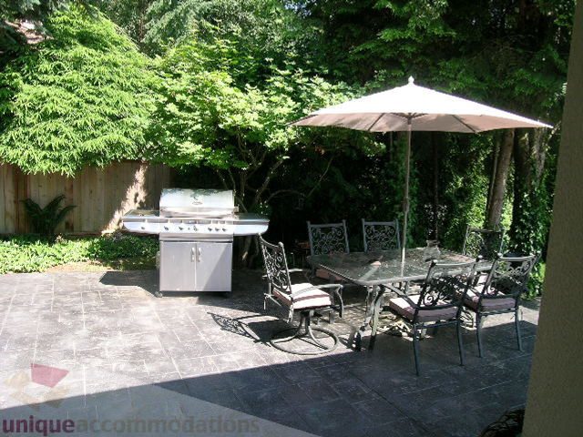 Furnished patio with outdoor dining set and umbrella, surrounded by lush greenery. - 4104 Sunnycrest drive, North Vancouver