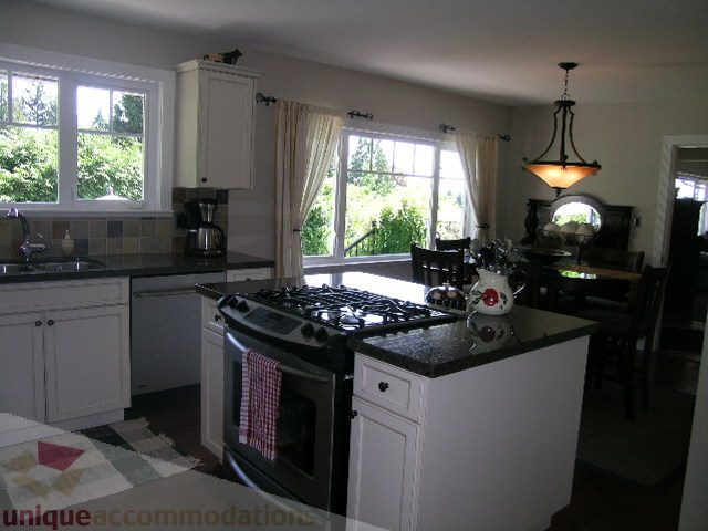 Bright kitchen with granite countertops, hardwood floors, and a view of lush greenery. - 4104 Sunnycrest drive, North Vancouver