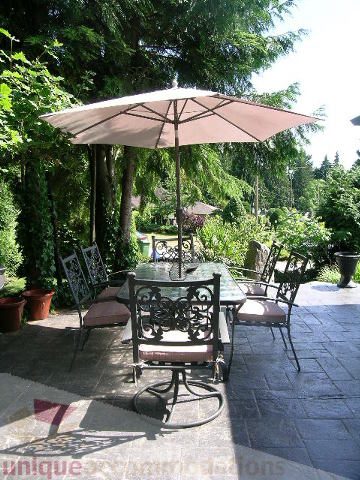 Furnished patio with outdoor furniture and a large umbrella, surrounded by lush greenery. - 4104 Sunnycrest drive, North Vancouver