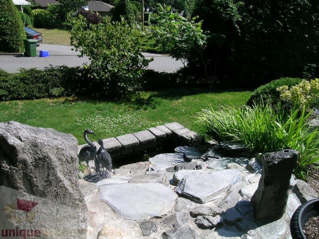 Furnished living room with stone fireplace and lush garden view. - 4104 Sunnycrest drive, North Vancouver