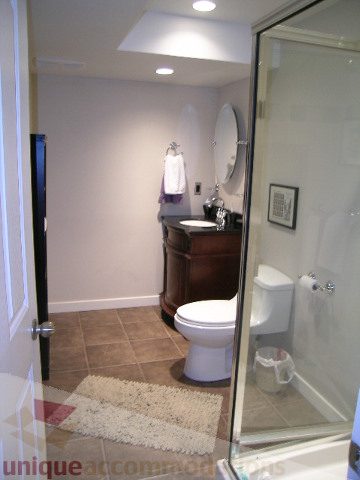 Furnished bathroom with a glass shower, wooden vanity, and a shaggy bath mat. - 4104 Sunnycrest drive, North Vancouver