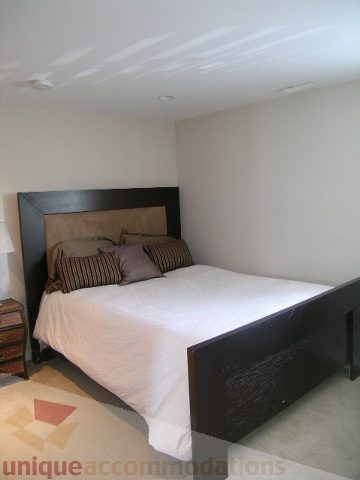 Spacious bedroom with a modern dark wood headboard and neatly made bed. - 4104 Sunnycrest drive, North Vancouver
