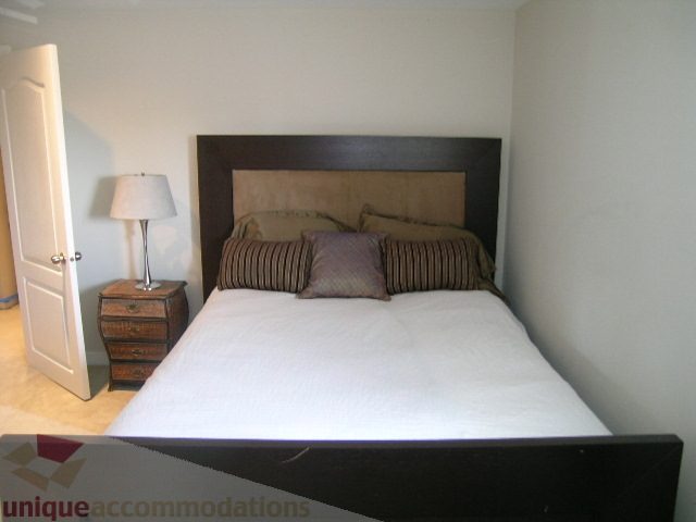 Spacious bedroom with a large bed, wooden headboard, and nightstands. - 4104 Sunnycrest drive, North Vancouver