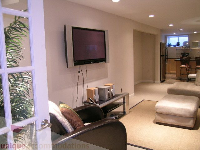 Spacious living room with modern TV, cozy seating, and open layout. - 4104 Sunnycrest drive, North Vancouver