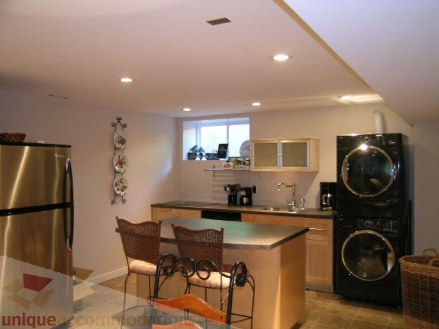Bright kitchen with stainless steel appliances and a bar counter, featuring a window with a view. - 4104 Sunnycrest drive, North Vancouver