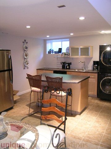 Bright kitchen with stainless steel appliances, tiled flooring, and a bar area with orange chairs. - 4104 Sunnycrest drive, North Vancouver