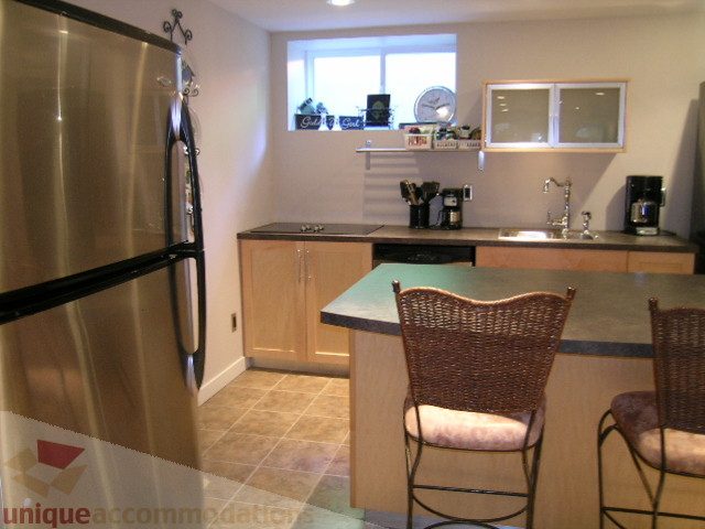 Bright kitchen with granite countertops, wooden bar stools, and a window view. - 4104 Sunnycrest drive, North Vancouver