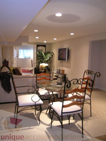 Furnished living room with wrought iron chairs and a glass-top table, modern lighting, and a flat-screen TV. - 4104 Sunnycrest drive, North Vancouver