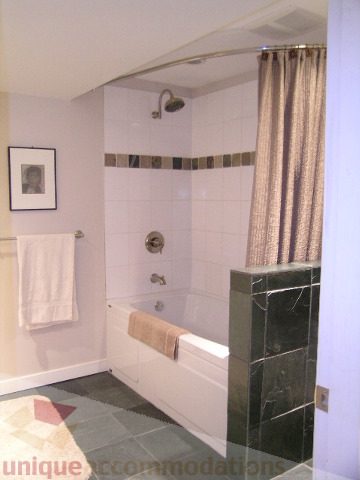 Bright bathroom with white tiles, shower curtain, and framed artwork. - 4104 Sunnycrest drive, North Vancouver