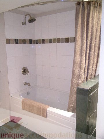 Bathroom with white tiles, shower curtain, and towel rack. - 4104 Sunnycrest drive, North Vancouver