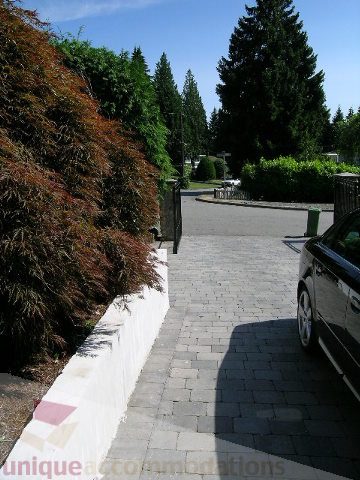 Paved walkway leading to a house with lush greenery and trees. - 4104 Sunnycrest drive, North Vancouver