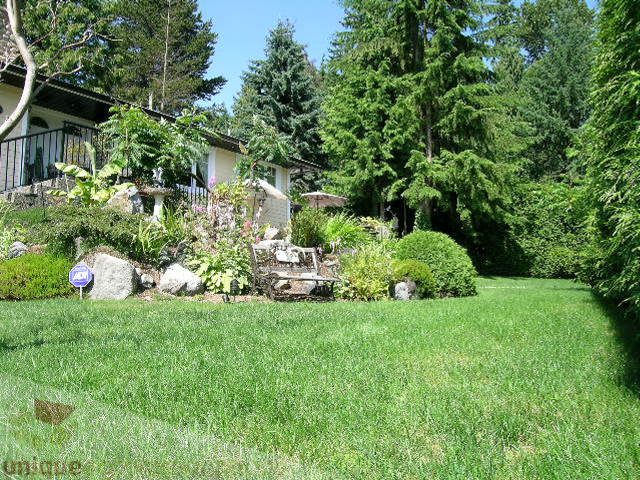 Bright living room with lush green lawn and evergreen trees. - 4104 Sunnycrest drive, North Vancouver