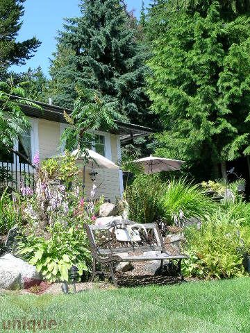 Furnished living room with cozy bench, lush greenery, and a view of the house. - 4104 Sunnycrest drive, North Vancouver