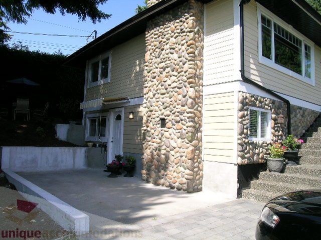 Bright living room with stone accent wall and patio access. - 4104 Sunnycrest drive, North Vancouver