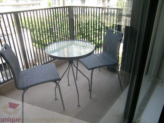 Furnished balcony with glass table and wicker chairs, overlooking greenery. - 705 - 1055 Homer Street, Vancouver Downtown
