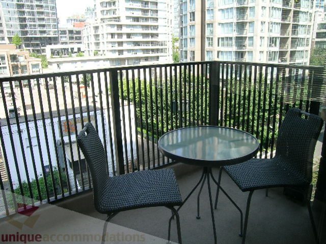 Furnished balcony with city view, black wicker furniture, and modern railings. - 705 - 1055 Homer Street, Vancouver Downtown