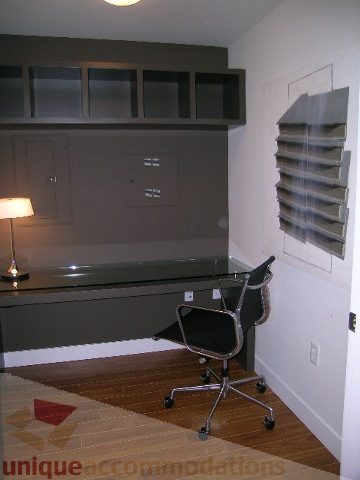 Furnished office with built-in shelves, hardwood floors, and a desk lamp. - 208 - 1833 Crowe St., Vancouver West Side