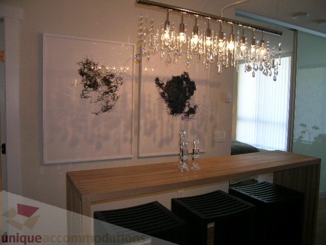 Bright kitchen with wooden countertops, modern chandelier, and abstract wall art. - 208 - 1833 Crowe St., Vancouver West Side