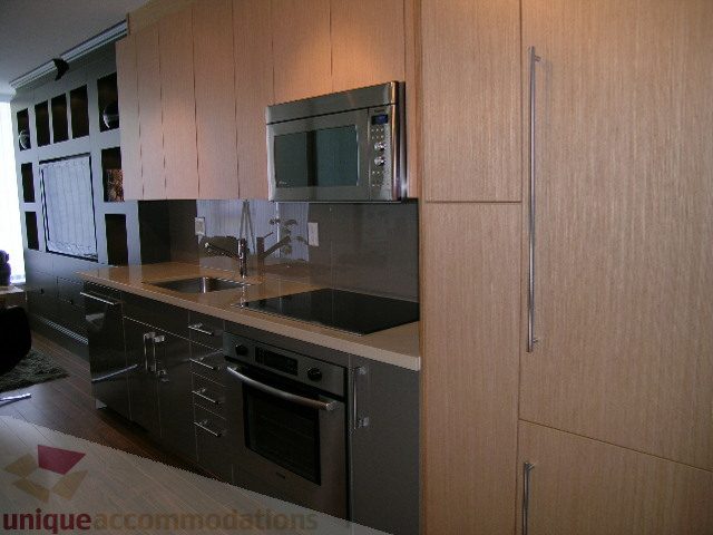 Bright kitchen with modern stainless steel appliances, black countertops, and hardwood floors. - 208 - 1833 Crowe St., Vancouver West Side