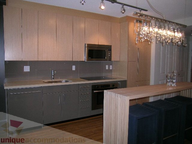 Bright kitchen with modern cabinetry, granite countertops, and a chandelier above the island. - 208 - 1833 Crowe St., Vancouver West Side