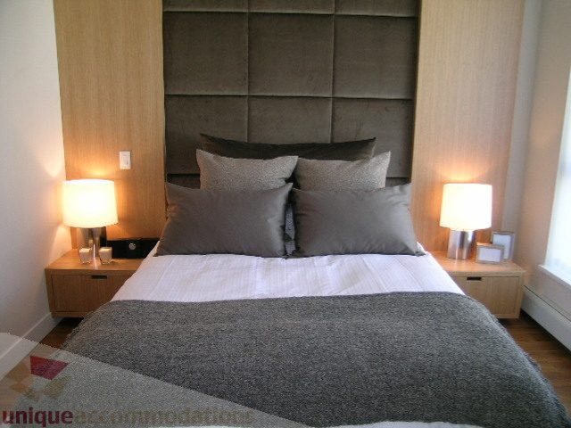 Furnished 1-bedroom condo with modern decor, gray bedding, and wooden headboard. - 208 - 1833 Crowe St., Vancouver West Side