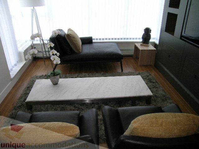 Bright living room with marble coffee table, black leather furniture, and hardwood floors. - 208 - 1833 Crowe St., Vancouver West Side