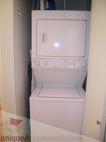 Bright laundry room with stacked washer and dryer, white countertops. - 405 - 233 Abbott Street, Vancouver Downtown