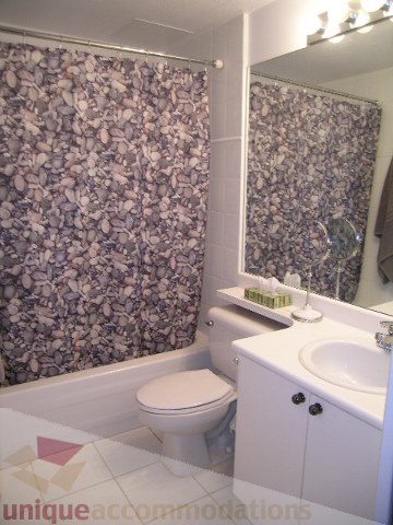 Bright bathroom with white countertops and pebble-patterned shower curtain. - 405 - 233 Abbott Street, Vancouver Downtown