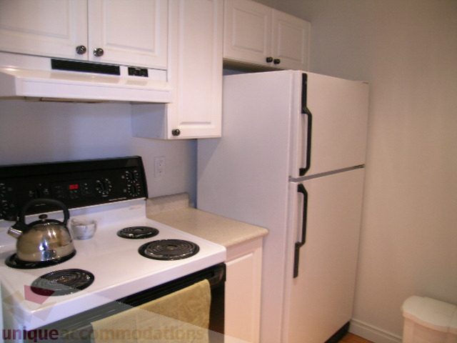 Bright kitchen with white appliances, countertop, and hardwood floors. - 405 - 233 Abbott Street, Vancouver Downtown