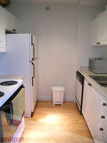 Bright kitchen with white cabinets, hardwood floors, and a small refrigerator. - 405 - 233 Abbott Street, Vancouver Downtown