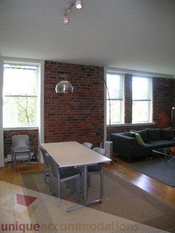 Bright living room with brick wall, hardwood floors, and large windows. - 405 - 233 Abbott Street, Vancouver Downtown
