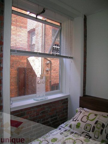 Bright bedroom with brick wall and window view, modern bedding. - 405 - 233 Abbott Street, Vancouver Downtown
