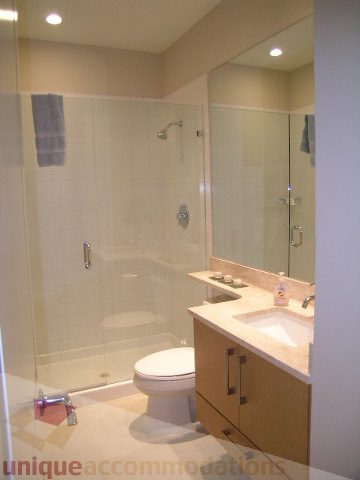 Bathroom with modern fixtures, glass shower, and wooden vanity. - 102 - 1333 West 11th Ave., Vancouver West Side