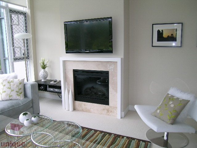 Bright living room with modern furniture, glass coffee table, and wall-mounted TV. - 102 - 1333 West 11th Ave., Vancouver West Side