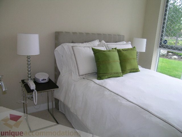 Bright bedroom with white bedding, green accent pillows, and a window view. - 102 - 1333 West 11th Ave., Vancouver West Side